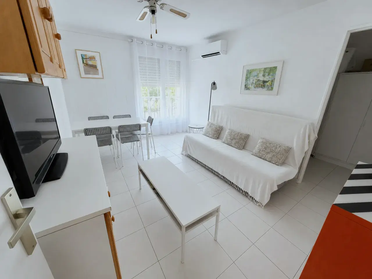 Pièce de vie lumineuse de l'appartement à Bormes-les-Mimosas : canapé-lit, coin repas et télévision